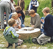 Das Foto zeigt eine Gruppe beim Mahlen von Korn.