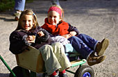 Das Foto zeigt zwei Kinder in einem Bollerwagen.