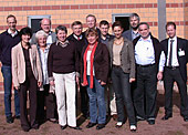 Gruppenfoto vor einer orangefarbenen Backsteinwand
