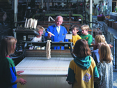 Das Bild zeigt Kinder bei der Besichtigung eines Webstuhls. Foto: LWL-Industriemuseum