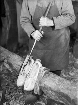 Holzschuhmacher beim Aushöhlen und Glätten der Schuhe mit dem Räumhaken