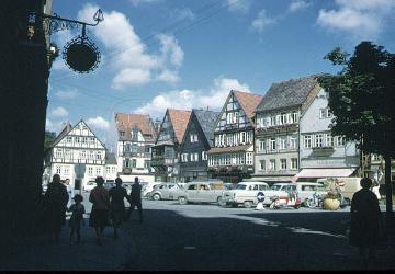 Rinteln-Altstadt, um 1961: Nordseite des Marktplatzes von Südosten - v.r.n.l.: Häuser  Nr. 11 und 12, Nr. 13 (Café Sinke), Nr. 14 und 15 (Engel Apotheke, ehemalige Universitäts- und Ratsapotheke, gegründet 1619), im Hintergrund: Haus Weserstraße 18 und Nr. 17, Neubau von 1910
