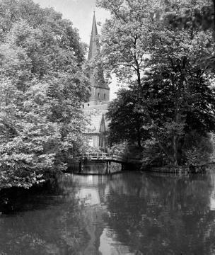 Am Papendiek: Blick über die Aa auf den von Bäumen eingerahmten Kirchturm von St. Remigius