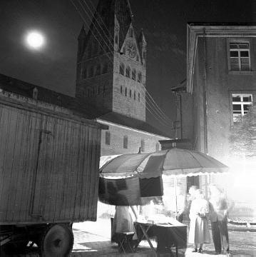 Allerheiligenkirmes: Verkaufsstand bei Nacht mit Blick zur Kirche St. Patrokli
