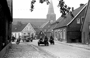 Ein Truppenverband der Waffen-SS fährt durch das Dorf, Militärfahrzeuge und Schaulustige auf der Dorfstraße. Die österreichische SS-Einheit  war von Herbst 1939 bis Frühjahr 1940 in Raesfeld einquartiert .