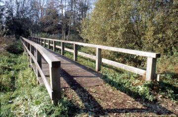 Holzbrücke am Feuchtbiotop Wienburgpark: Ökologisch gestaltetes Naherholungsgebiet, angelegt 1986/87 auf dem ehemaligen Gut Nevinghoff