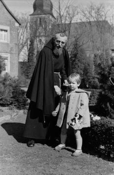 Kapuzinerpater Mainolf mit Sohn von Günter Rhode, Nottuln - im Hintergrund die St. Martinus-Kirche, undatiert, Ende 1940er Jahre?
