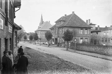 Harsewinkel-Dorfmitte, Gütersloher Straße (nun mit Kopfsteinpflasterung): Dampfmühle Seppelfricke/Bröskamp (links), "Richter und Post" (rechts). Im Hintergrund: Turm der St. Lucia-Kirche. Undatiert, um 1940?