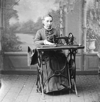Fräulein Jäger, Schwester des Harsewinkeler Buchbinders und Fotografen Johann Hermann Jäger. Atelierinszenierung mit Nähmaschine. Undatiert, um 1880?