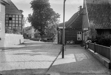 Ortskern Enger, Bäckerstraße [?] mit Brücke über den Boldammbach. Rechts: Friseur Kach und Fassadenschild "Hannoverscher Kurier". Undatiert, 1940er Jahre?