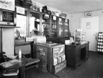 Laden der Esso-Tankstelle K. Niggemann [vermutet] - Hamm-Rhynern, Werler Straße (B 63) Ecke Rhynerberg. Im Warenangebot unter anderem: ESSO-Motoröl, technische Artikeln, Coca-Cola, "Moccarahm-Milch" und Süßigkeiten. Undatiert, um 1955.