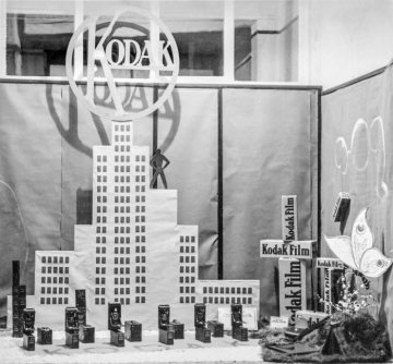 Werbung für Kodak-Fotoapparate und Kodak-Filme, 1920er Jahre: Schaufenster des Fotoateliers Josef Viegener an der Oststraße 47 in Hamm - dekoriert mit einer Papiernachbildung des Eastman-Kodak-Towers in Rochester, N.Y. (USA). Undatiert, um 1926 [?]
