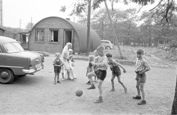 Kinder beim Ballspielen vor einer Nissenhütte [Notwohnung] von 1947 in Rauxel, 1962.