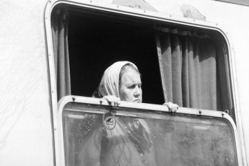 Kriegsflüchtling aus Bosnien [1992-1995 Kriegsgebiet im Rahmen der Jugoslawienkriege 1991-1999] in einem Sonderzug des Roten Kreuzes nach der Ankunft im Hauptbahnhof Castrop-Rauxel, August 1992. [Die Flüchtlinge wurden anschließend von Rot-Kreuz-Helfern zur Unterkunft im Vinckehof nach Castrop-Rauxel-Ickern begleitet.]
