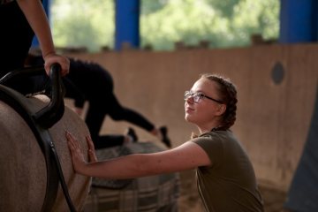Akrobatik zur Pferde: Voltigiergruppe beim Training - zur Schonung des Pferderückens hier auf einem mit Teppichen bezogenen Holzbock. Lemgo, 2019.