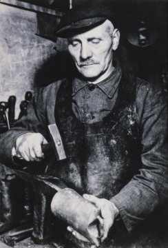 Wilhelm Krämer, der letzte Schellenschmied im Siegerland (1877-1966, tätig bis 1950) vor seiner Schmiede in Hilchenbach-Grund. Undatiert, um 1950?