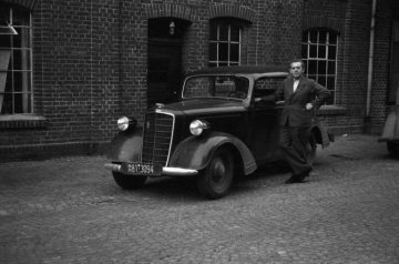 Strumpffabrik Gebr. Rhode Strickereien GmbH, Nottuln: Chauffeur Klemens Stahl mit Firmenwagen vor dem Betriebsgebäude, um 1948