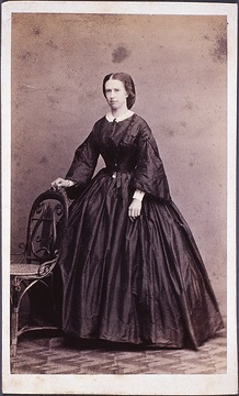 Stehende Frau, auf Stuhl gestützt. Cäcilie Freifrau von Droste zu Hülshoff, geborene Freiin von Elmendorff. Papierfotografie