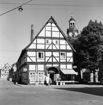 Rinteln-Altstadt, 1961: Haus Kirchplatz Nr. 8 mit Feinkosthandel Sasse (Ansicht von Osten), links die Kreuzstraße mit den Fronten der Häuserzeile Kirchplatz Nr. 7-1, rechts die St. Nicolai-Kirche mit Kirchplatz