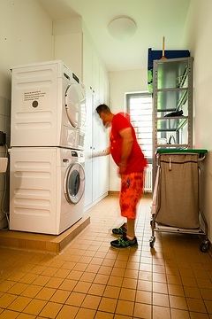 Klinikalltag von Patienten im LWL-Zentrum für Forensische Psychatrie in Lippstadt: Patient im Wäscheraum bei der Bedienung einer Waschmaschine