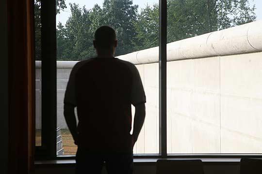 Foto: Mann schaut durchs Fenster auf Mauer Foto: Mann schaut durchs Fenster auf Mauer
