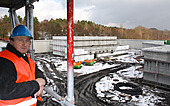 Ein Mann mit Helm steht auf einem Baugerüst über einer verschneiten Baustelle Ein Mann mit Helm steht auf einem Baugerüst über einer verschneiten Baustelle