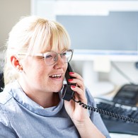 Portrait einer Mitarbeiterin, die in einem Büro am Schreibtisch sitzt und telefoniert Portrait einer Mitarbeiterin, die in einem Büro am Schreibtisch sitzt und telefoniert