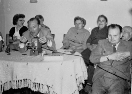 Das Foto zeigt mehrere Personen mit einem Diaprojektor