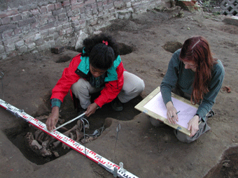 Zwei Frauen knien vor einem Skelett, vermessen und zeichnen es. Foto: LWL/R. Klostermann. 