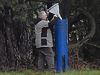 Ein Mann entnimmt eine Wasserprobe aus dem Regensammler