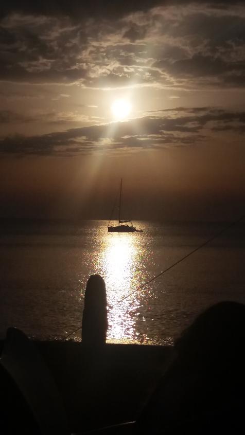 Die Sonne steht tief über dem Meer und taucht alles in ein fahles Licht, auf dem Wasser ist die Silhouette eines Segelboots zu erkennen. Foto: Robert Laube (vergrößerte Bildansicht wird geöffnet)