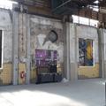 Die hohen Fenster eines Industriegebäudes sind mit Planen abgedeckt, auf denen Fotomotive von Fabriken zu sehen sind. (vergrößerte Bildansicht wird geöffnet)
