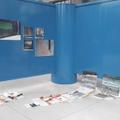 Fünf Bilder in unterschiedlichen Formaten hängen auf der Fläche einer blauen Wand, an der angrenzenden freien Fläche lehnen zwei weitere Bilder. (vergrößerte Bildansicht wird geöffnet)