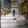 Ein Fahrradfahrer in Schutzkleidung fährt in einem Industriekomplex hinter einer Absperrung. (vergrößerte Bildansicht wird geöffnet)