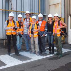 Eine Gruppe von sieben Personen posiert in Sicherheitswesten und Schutzhelmen für ein Foto. (vergrößerte Bildansicht wird geöffnet)