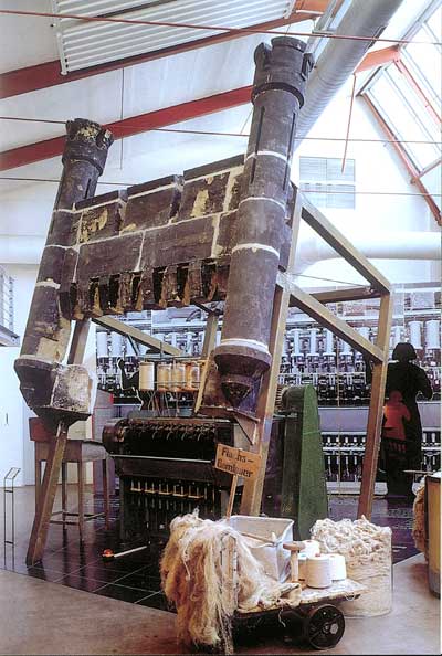 Fragmente vom Schornsteinkopf der Spinnerei in einer Museumsinszenierung mit alter Spinnmaschine