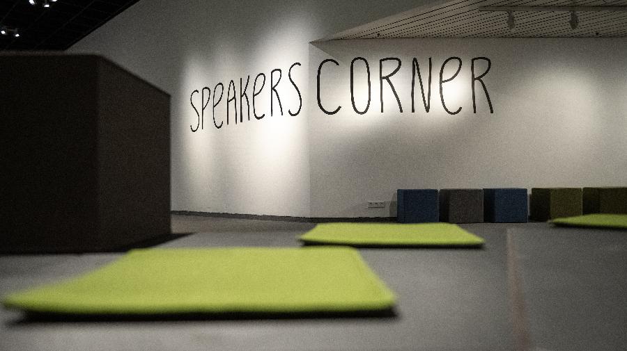 Raumansicht mit leeren Sitzplätzen und Schriftzug Speakers Corner an der Rückwand.