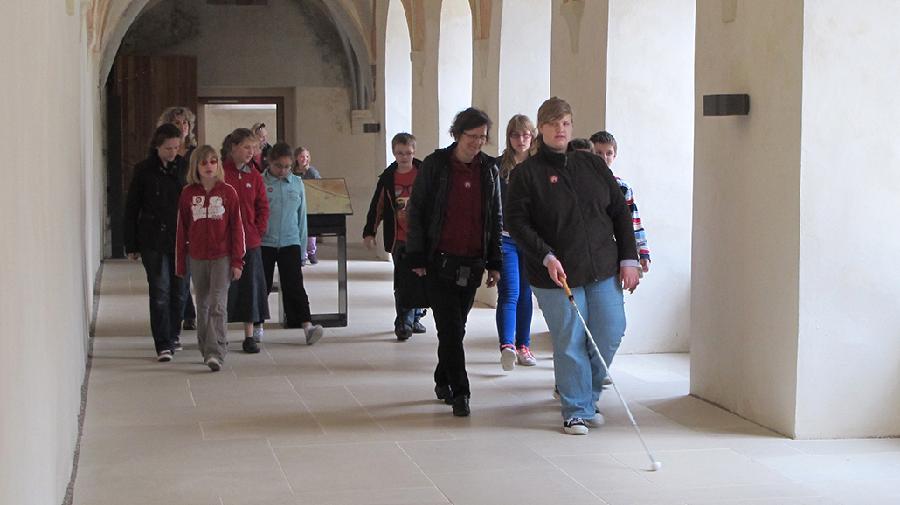 Eine Gruppe von blinden und sehenden Jugendlichen im Kreuzgang