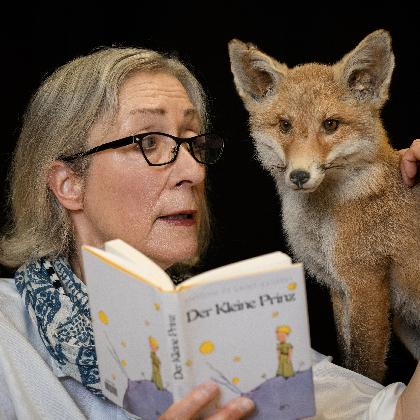 Beate Reker hält das Buch vom Kleinen Pronzen in der Hand und umfasst mit der anderen einen Fuchs.