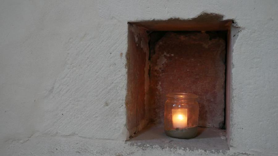Ein Teelicht brennt in einer Nische des Klostergebäudes