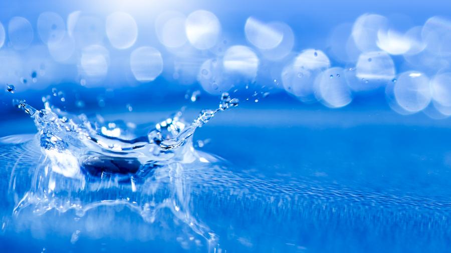 Nahaufnahme eines Wassertropfens der auf Wasser trifft.