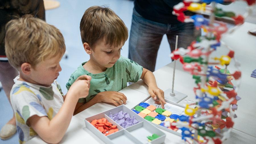 Zwei Kinder bauen mit einem bunten DNA-Baukasten eine DNA-Doppelhelix nach.