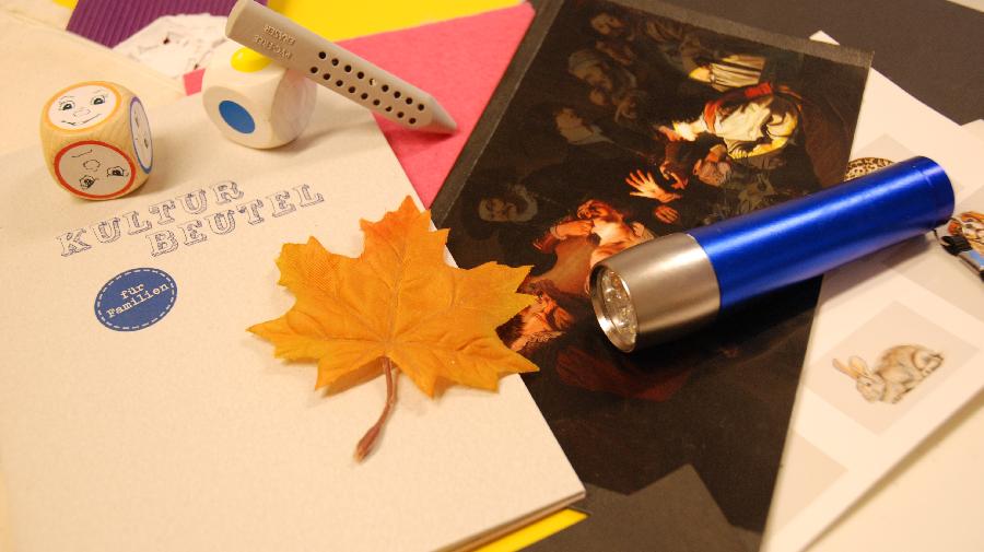 Verschiedene Materialien und Objekte auf einem Tisch. Darunter Würfel, Laubblatt und Block.