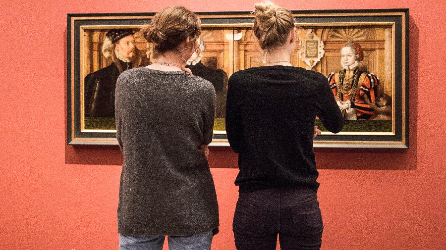 Zwei Personen betrachten ein längliches Gemälde.