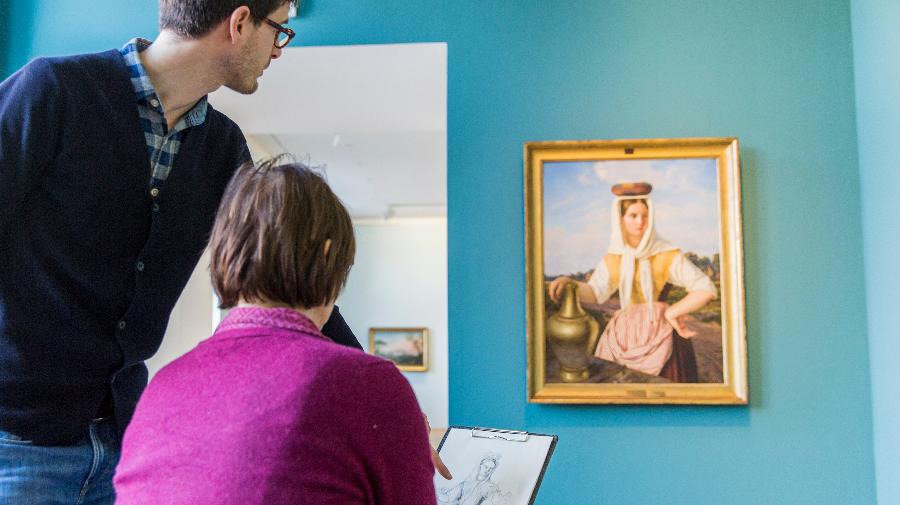 Eine Dame malt unter Anleitung ein Bild.