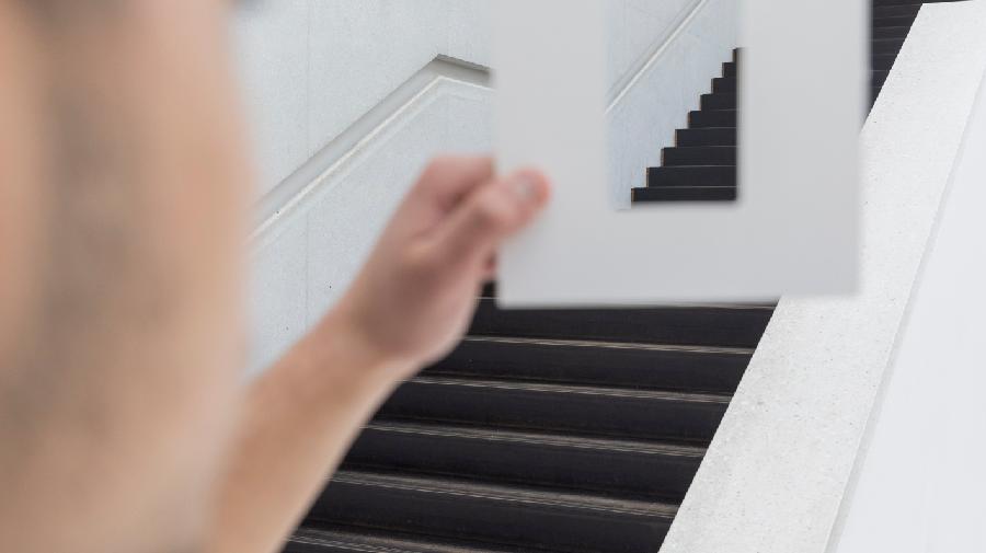 Junge hält Rahmen aus Papier hoch und guckt durch.