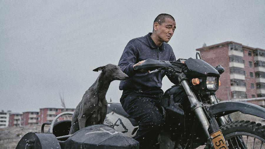 Filmszene aus Balck Dog. Ein Mann mit einem Hund auf einem Motorrad.