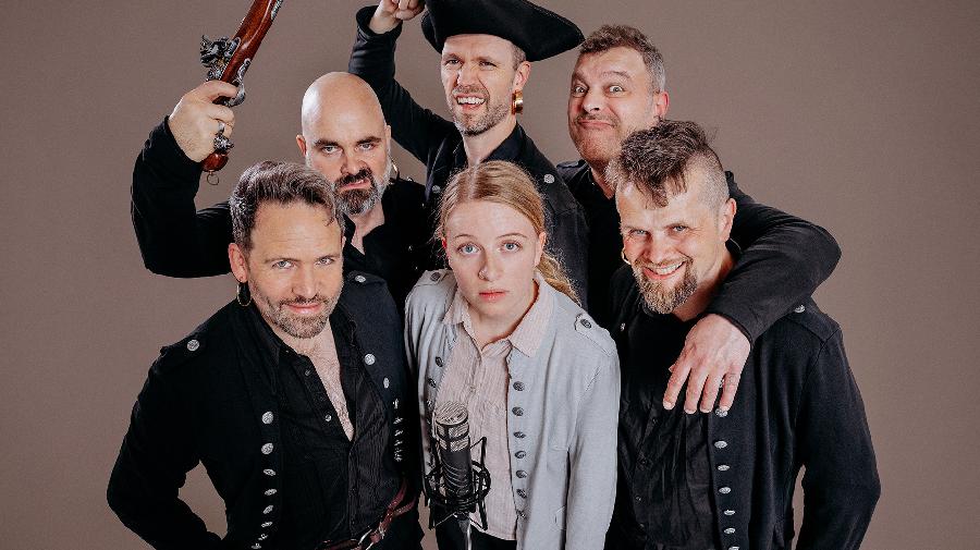 Sechs als Pirat:innen verkleidete Menschen blicken hoch in die Kamera.