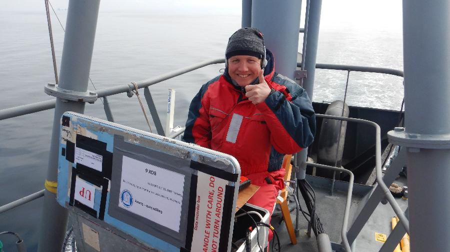 Johannes Baltzer sitzt an Deck eines Schiffes, vor sich Forschungsgeräte.