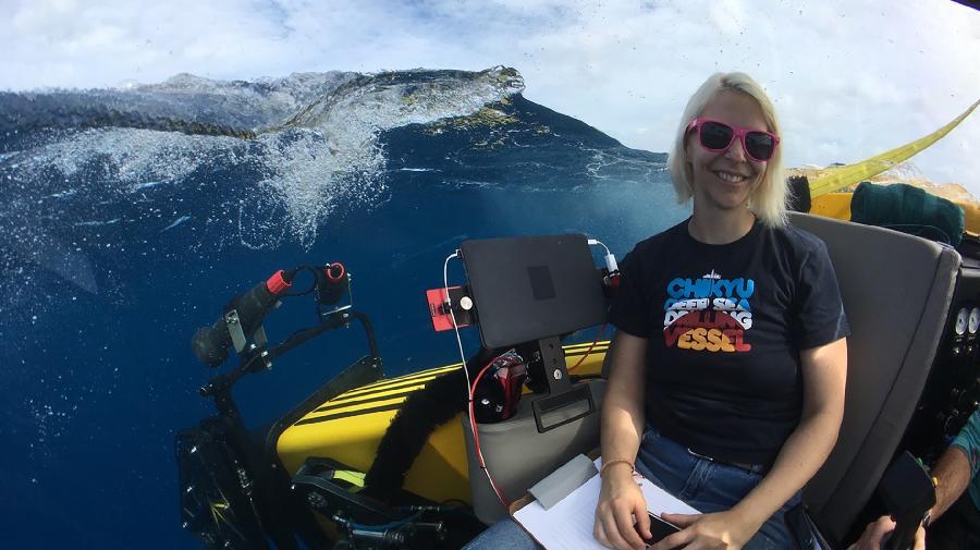 Florence Schubotz im Forschungsboot, neben ihr Forschungsgeräte und eine Welle.